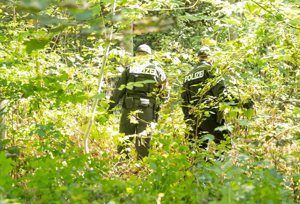 2 uniformed German police search a wooded area for clues