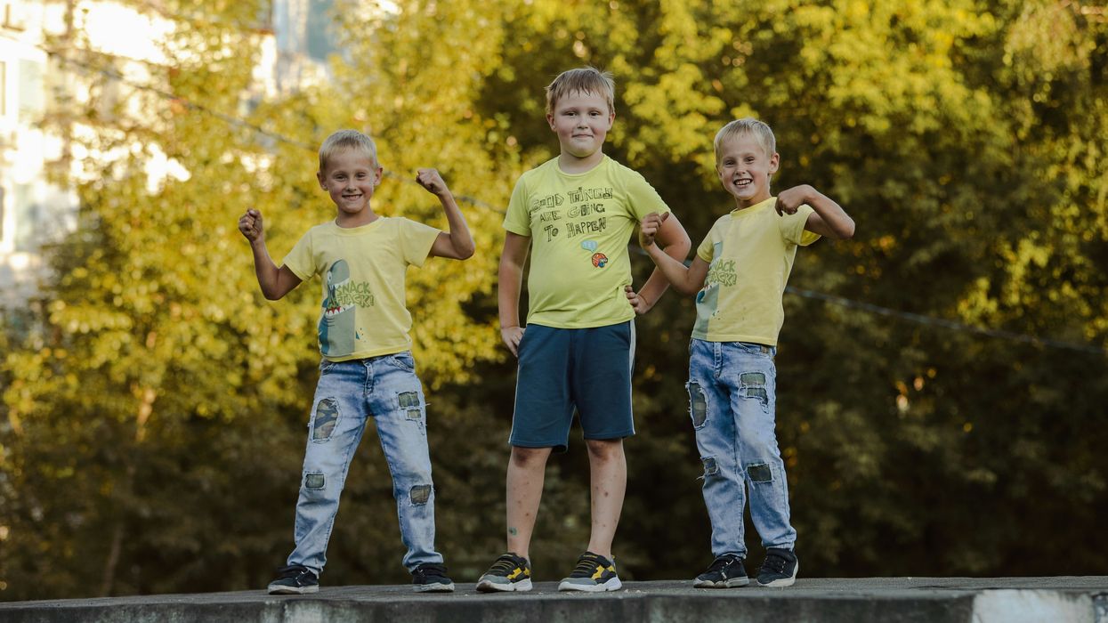 3 brothers standing on gray concrete wall