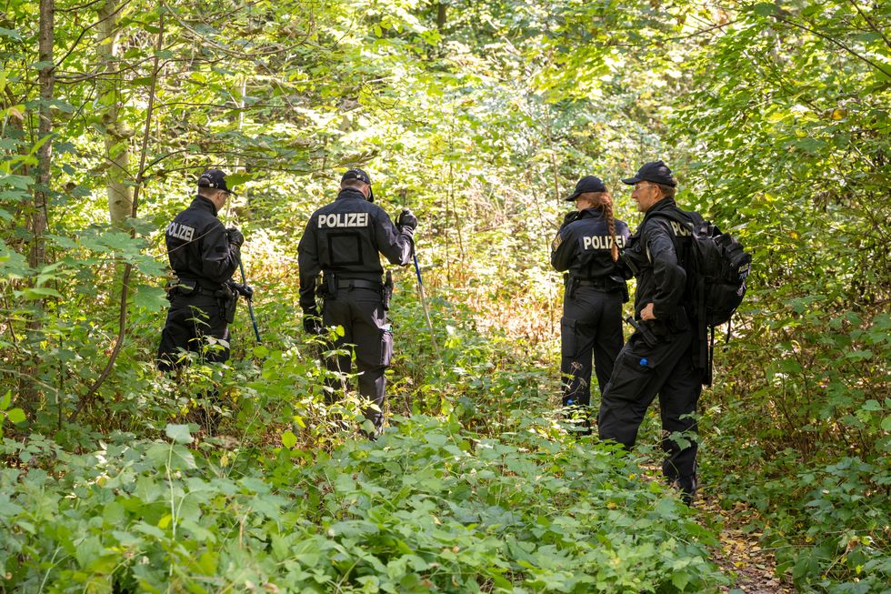 4 uniformed German police search a wooded area for clues