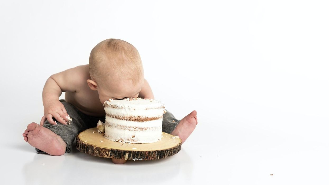 A baby has their face in a cake