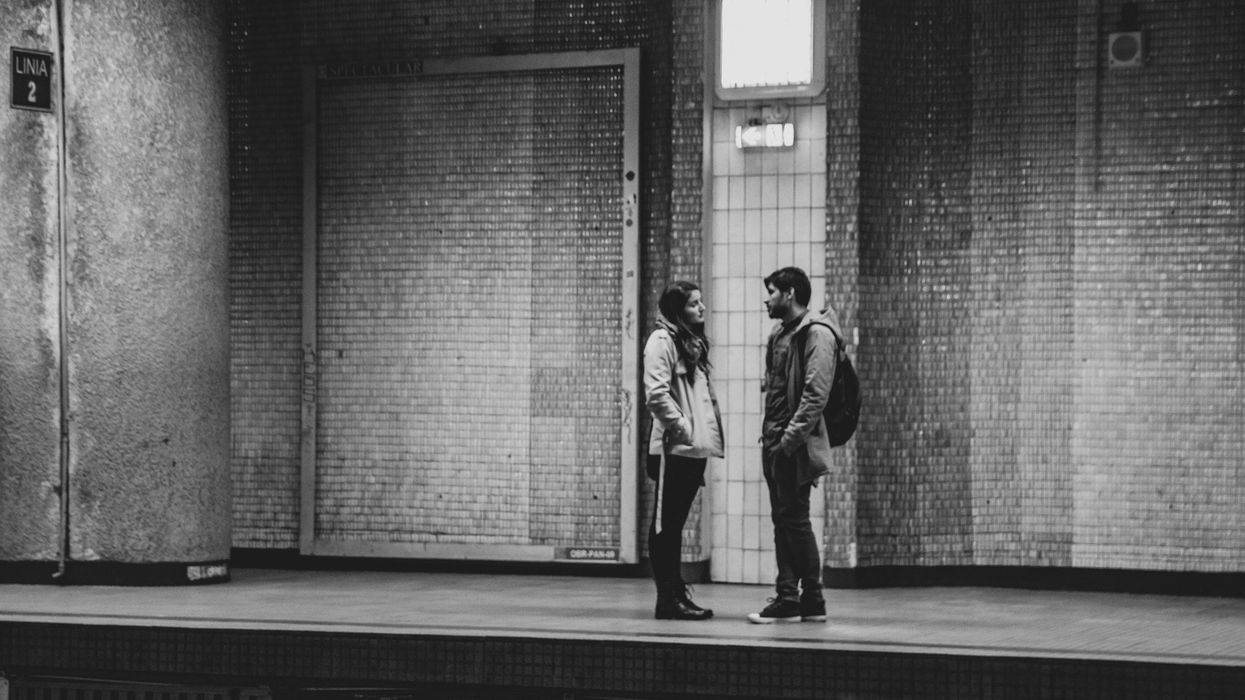 A black and white photo of a couple (guy and girl) in a tense conversation while standing on a train platform.