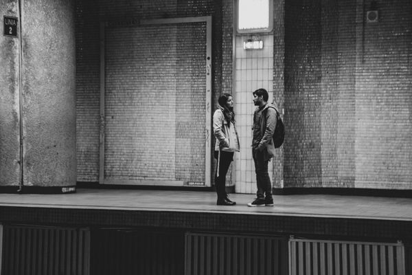 A black and white photo of a couple (guy and girl) in a tense conversation while standing on a train platform.