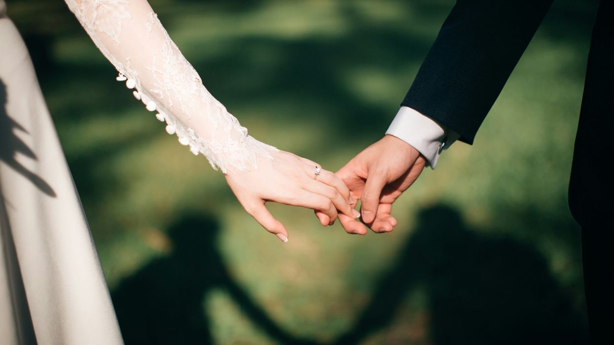 A bride's hand touching a groom's hand