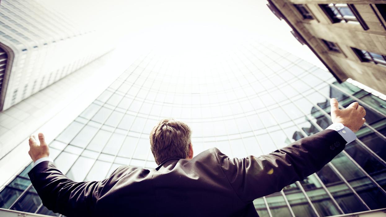 A businessman looking up with outstretched arms