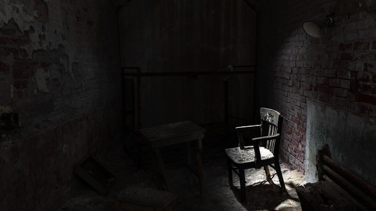 A chair lit by natural light in a dark room.