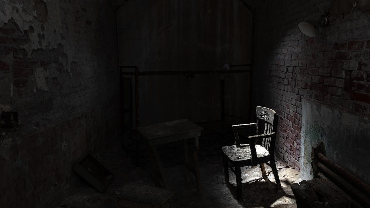 A chair lit by natural light in a dark room.