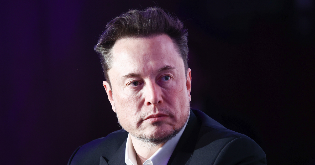A closeup shot of Elon Musk's face. He is looking off toward the right of the frame with a slight frown.