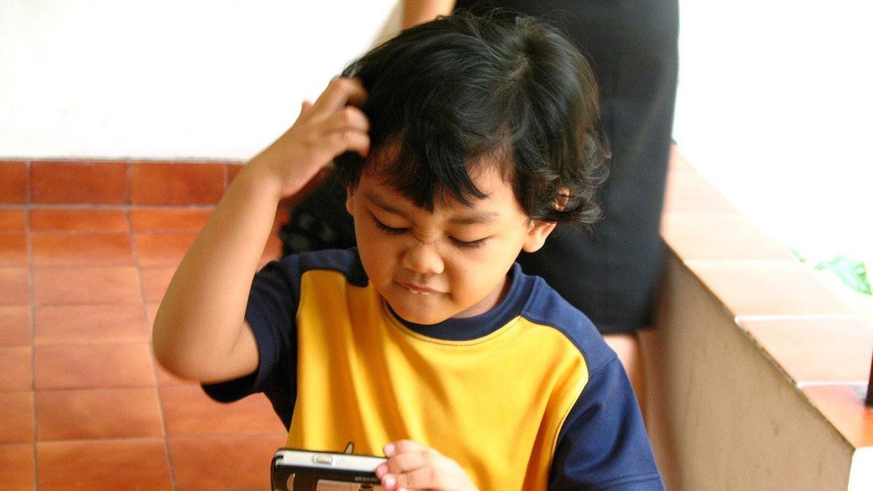 A confused young man looks at a picture on a phone