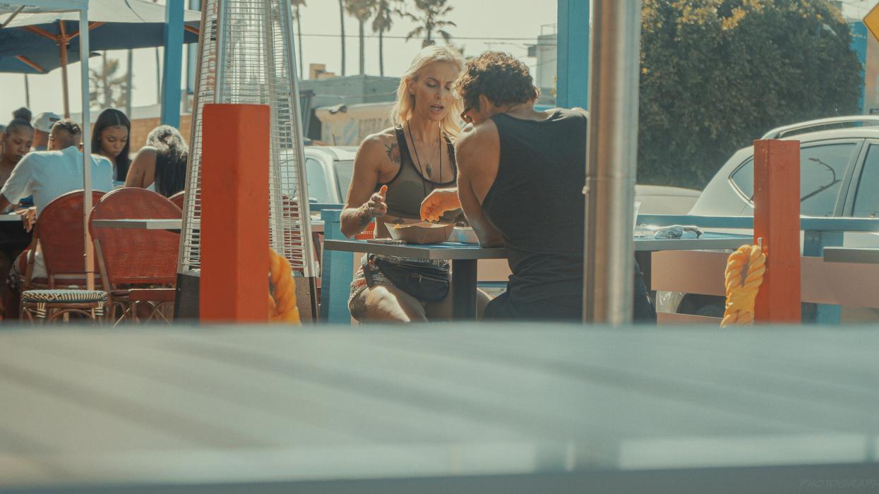 A couple eating outside, near a beach.