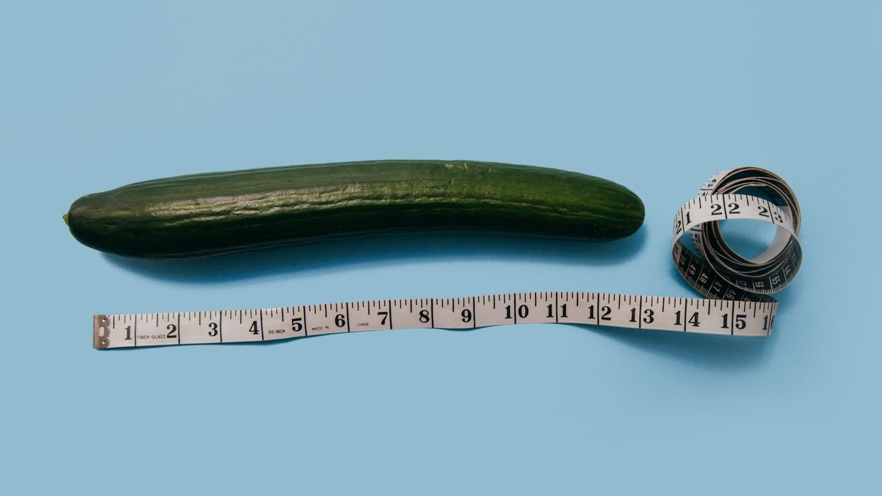 A cucumber, sits along side measuring tape.