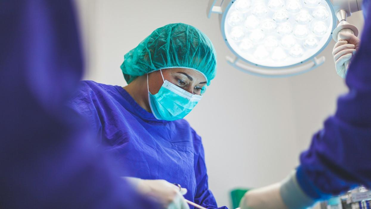 A female dentist works on a patient under the light.