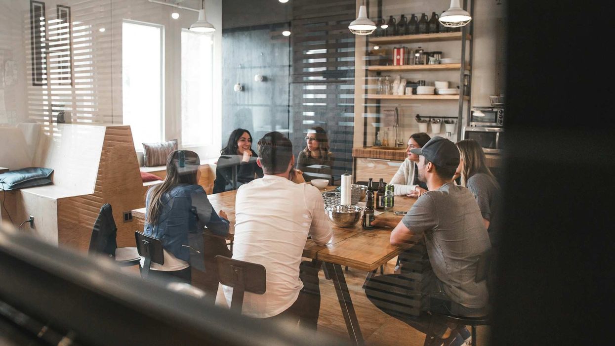 A group of co-workers sit a table in a conference room in a laid back, modern setting.