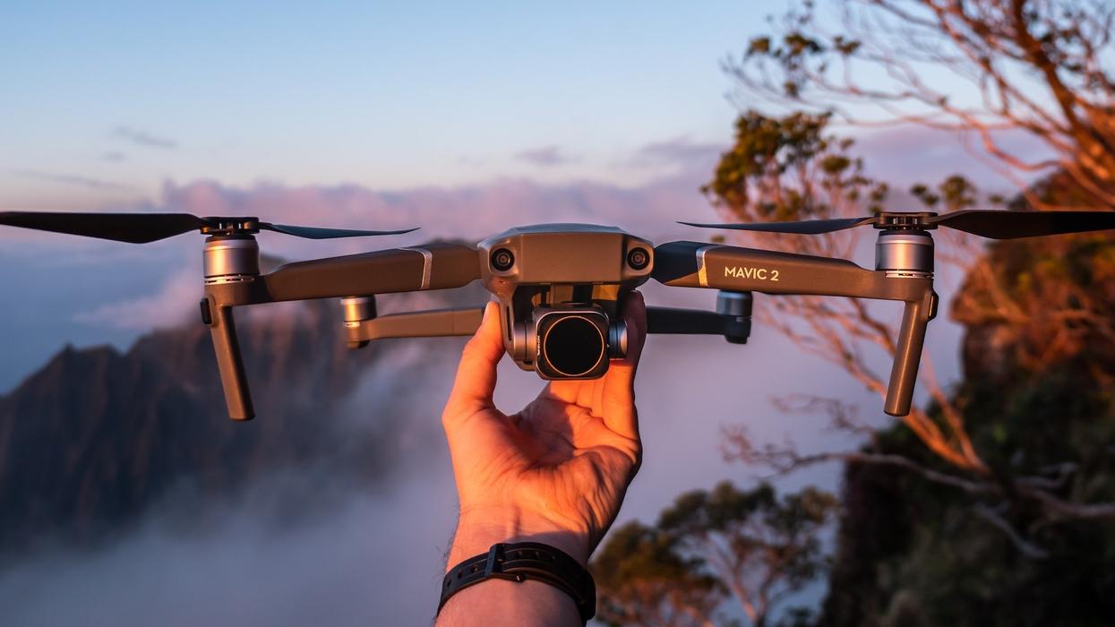 A hand holds a camera/flying drone