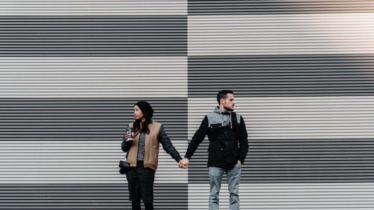 A man and a woman holding hands and looking in the opposite directions