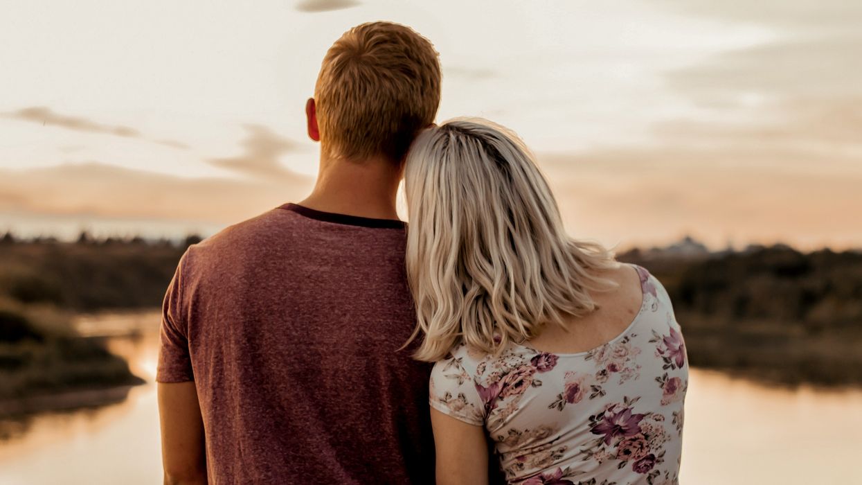A man and a woman resting their heads on one another staring into the distance.