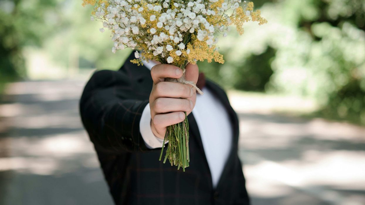A man blocking his face with a bouquet of flowers