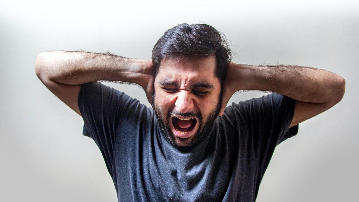 A man covers his ears and screams in frustration