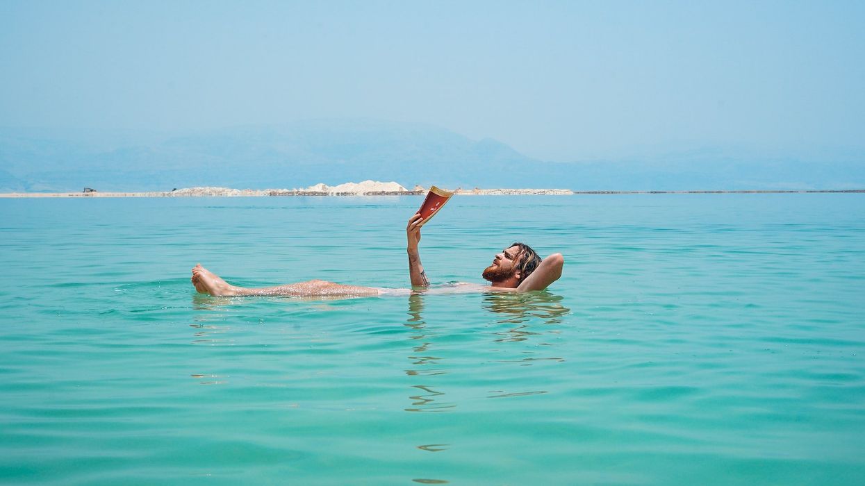 A man floats on his back in the ocean, while reading a book