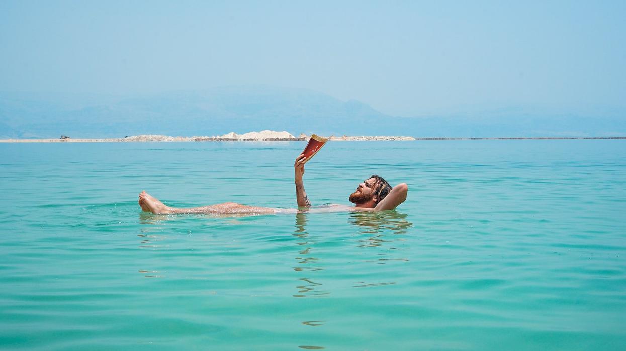 A man floats on his back in the ocean, while reading a book