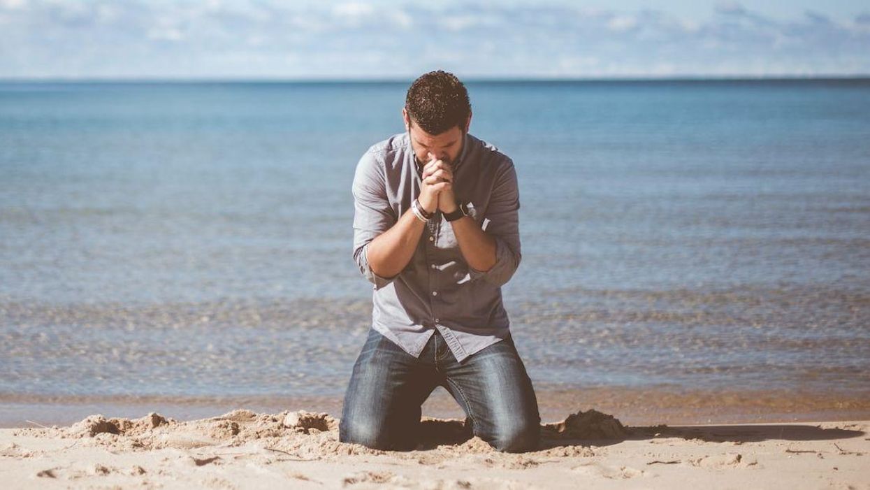 A man giving thankful prayers on a beach