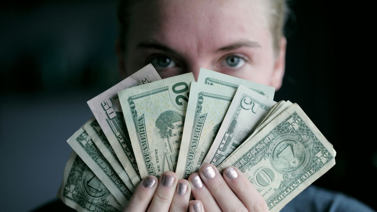 A man holding a fan of dollar bills