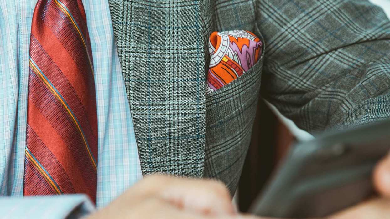 A man in a suit with a red tie and a pocket square