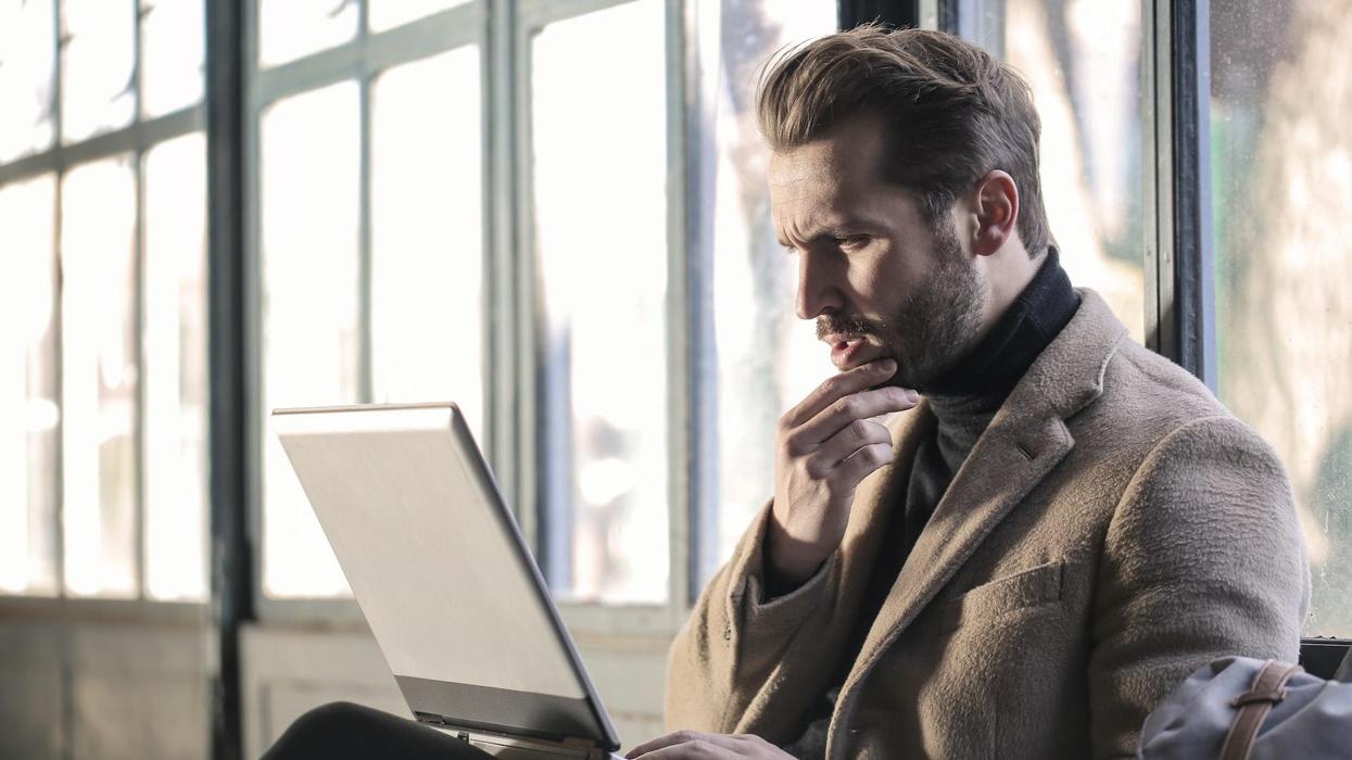 A man is on a computer with a confused face