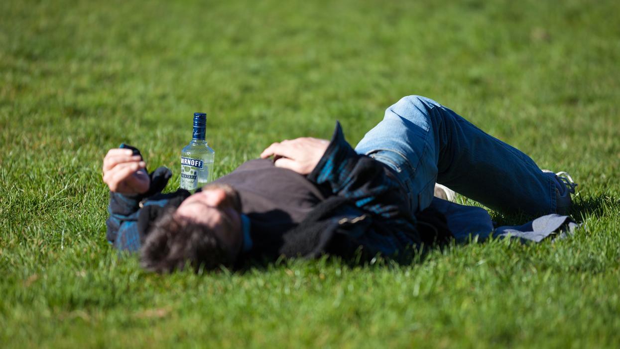 a man laying in the grass with a bottle of beer