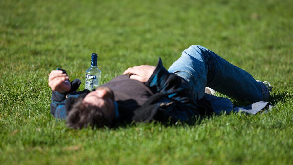 a man laying in the grass with a bottle of beer