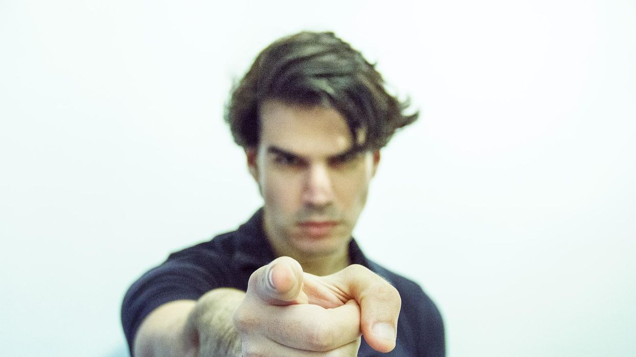 A man points into the camera with an angry scowl