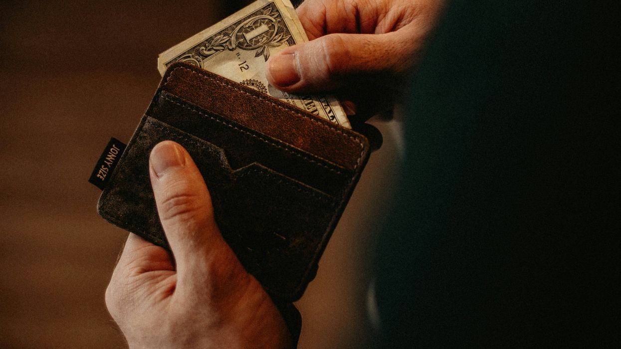 A man pulling a dollar bill out of a wallet