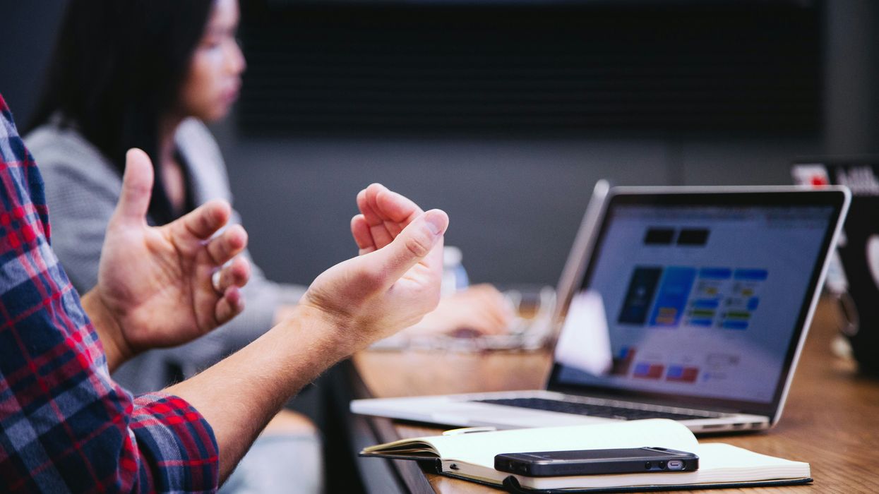 A man raising his hands in front of his laptop
