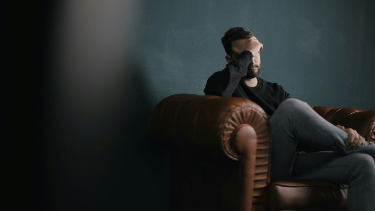 A man sitting on a sofa with his head in his hands.