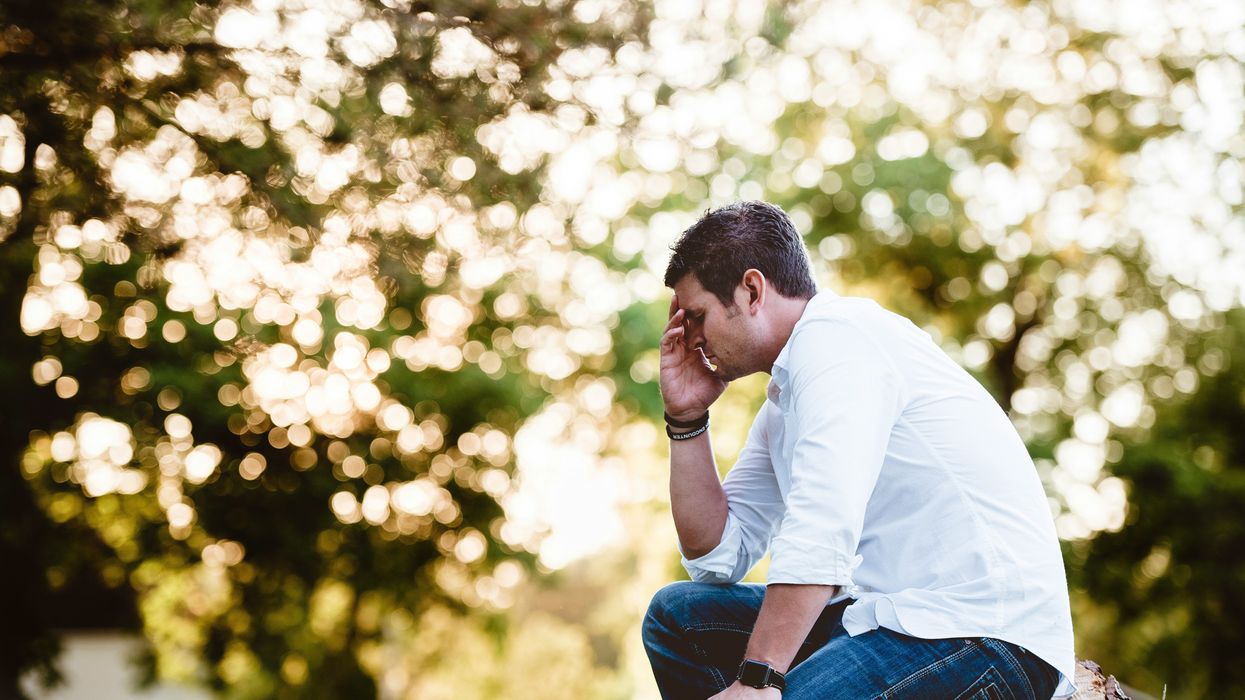 A man sitting outside with his head in his hands
