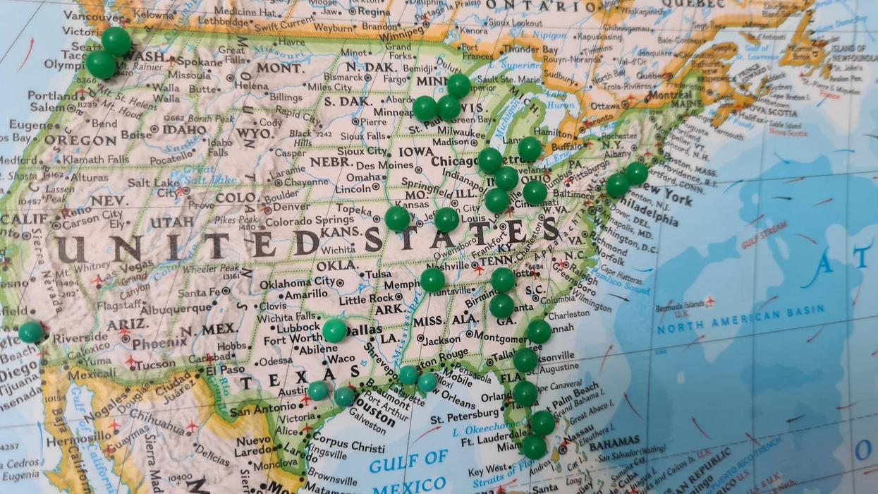 A map of the USA with green thumbtacks sticking in certain cities