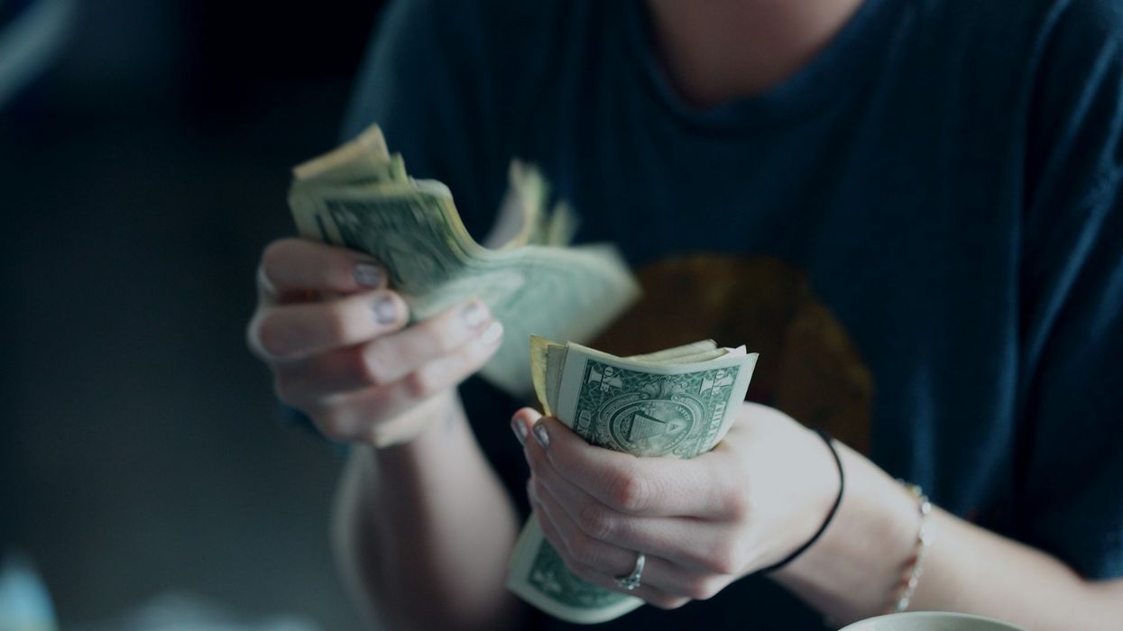 A mid-section shot of a woman counting one dollar bills.