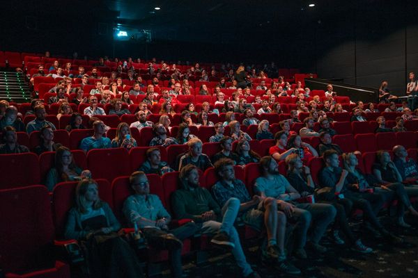 A movie theater full of people watch the screen