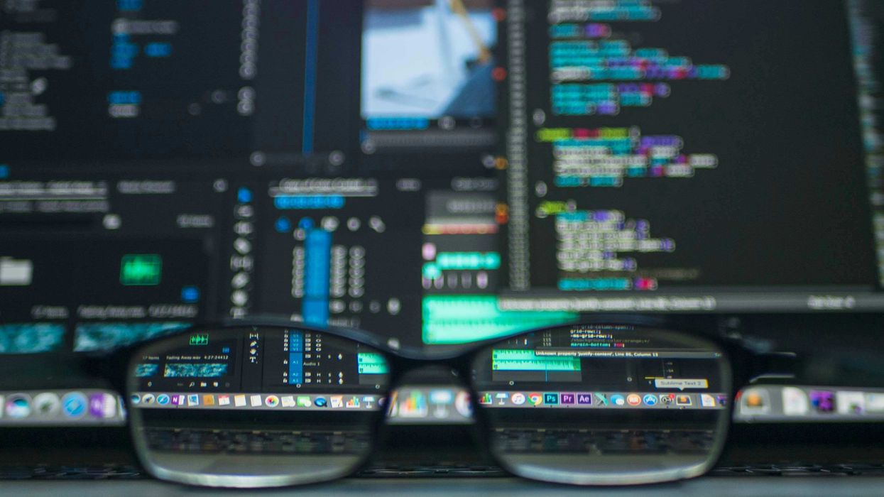 A pair of black glasses in front of multiple computer monitors