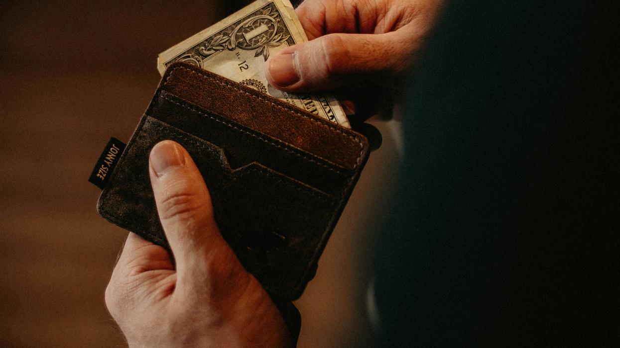 A pair of hands pulling money out of a wallet