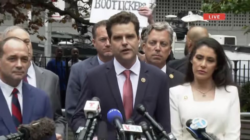 A protester holds a sign behind Republicans gathered outside Manhattan courthouse