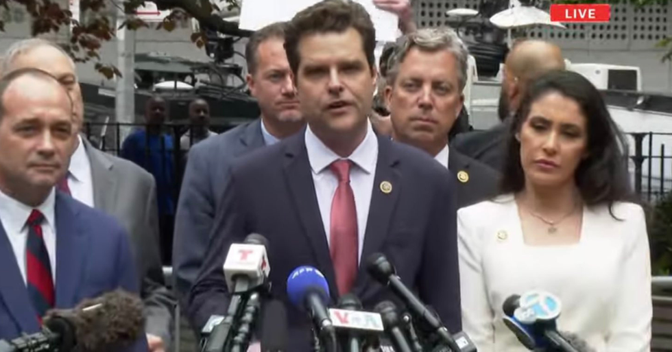 A protester holds a sign behind Republicans gathered outside Manhattan courthouse