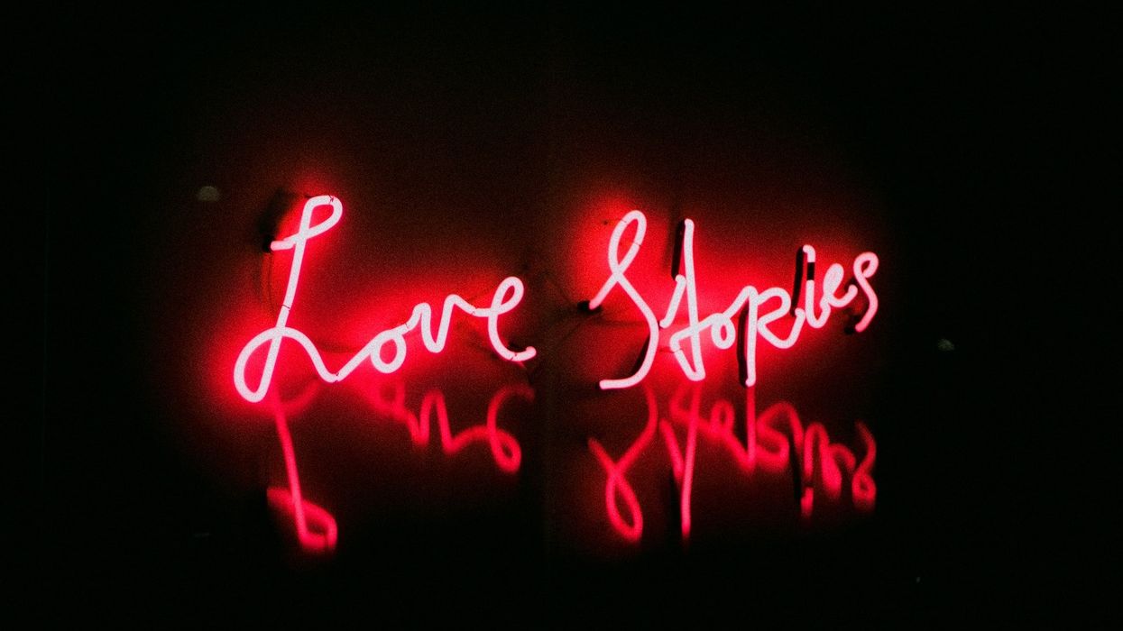 A red neon sign that says Love Stories and it's reflection