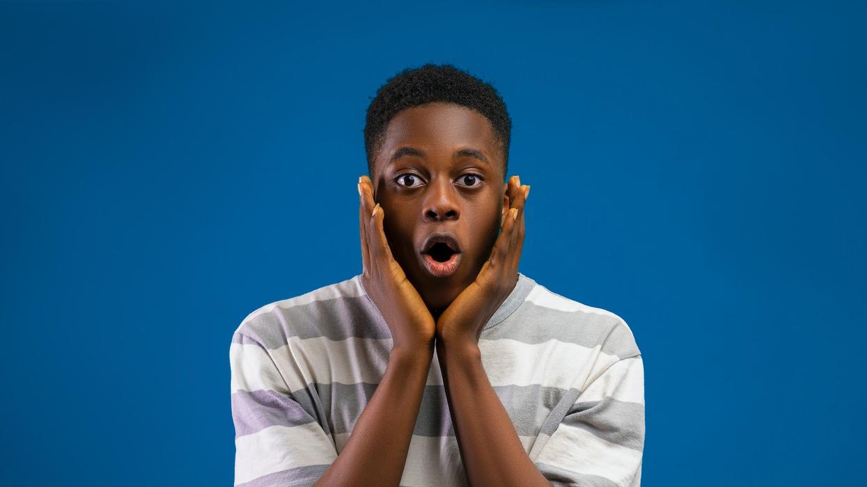 A shocked young man cups his face with his hands
