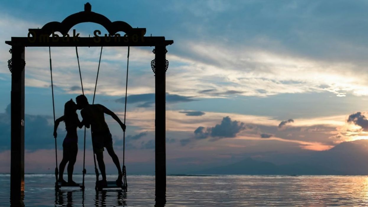 A silhouetted couple kissing in front of beach sunset