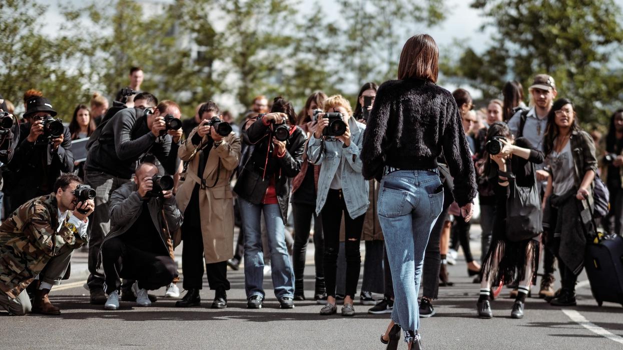 A well dressed woman walks towards the paparazzi