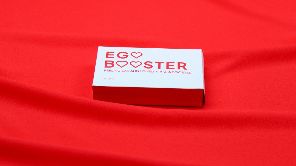 A white matchbox with the title "Ego Booster" sits on a red, satin background.