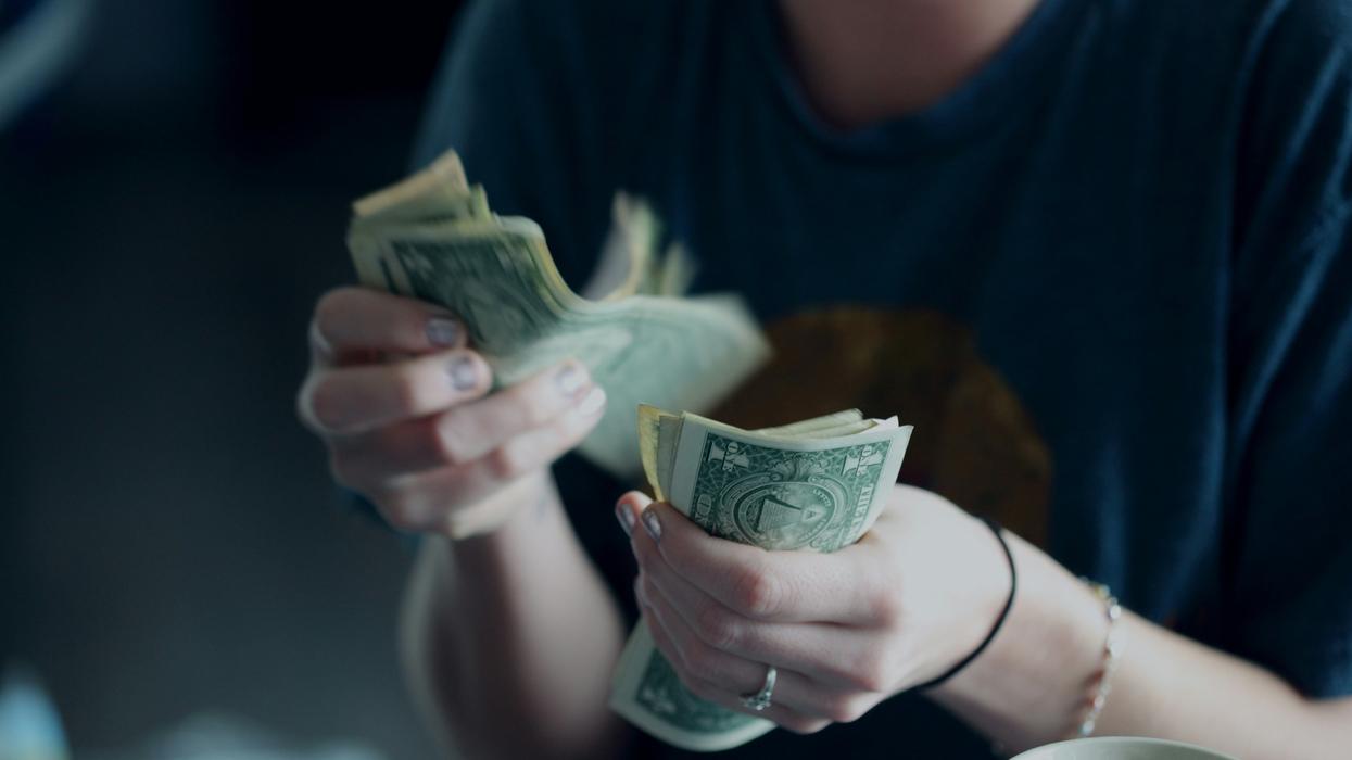 A woman counting a large pile of one dollar bills