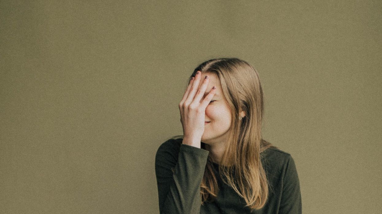 A woman face palms and smirks