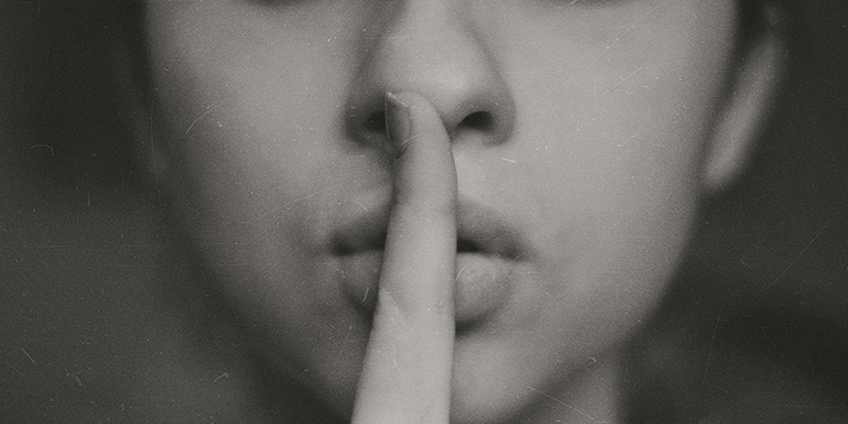 A woman holding her finger in front of her mouth.
