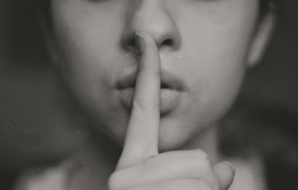 A woman holding her finger in front of her mouth.